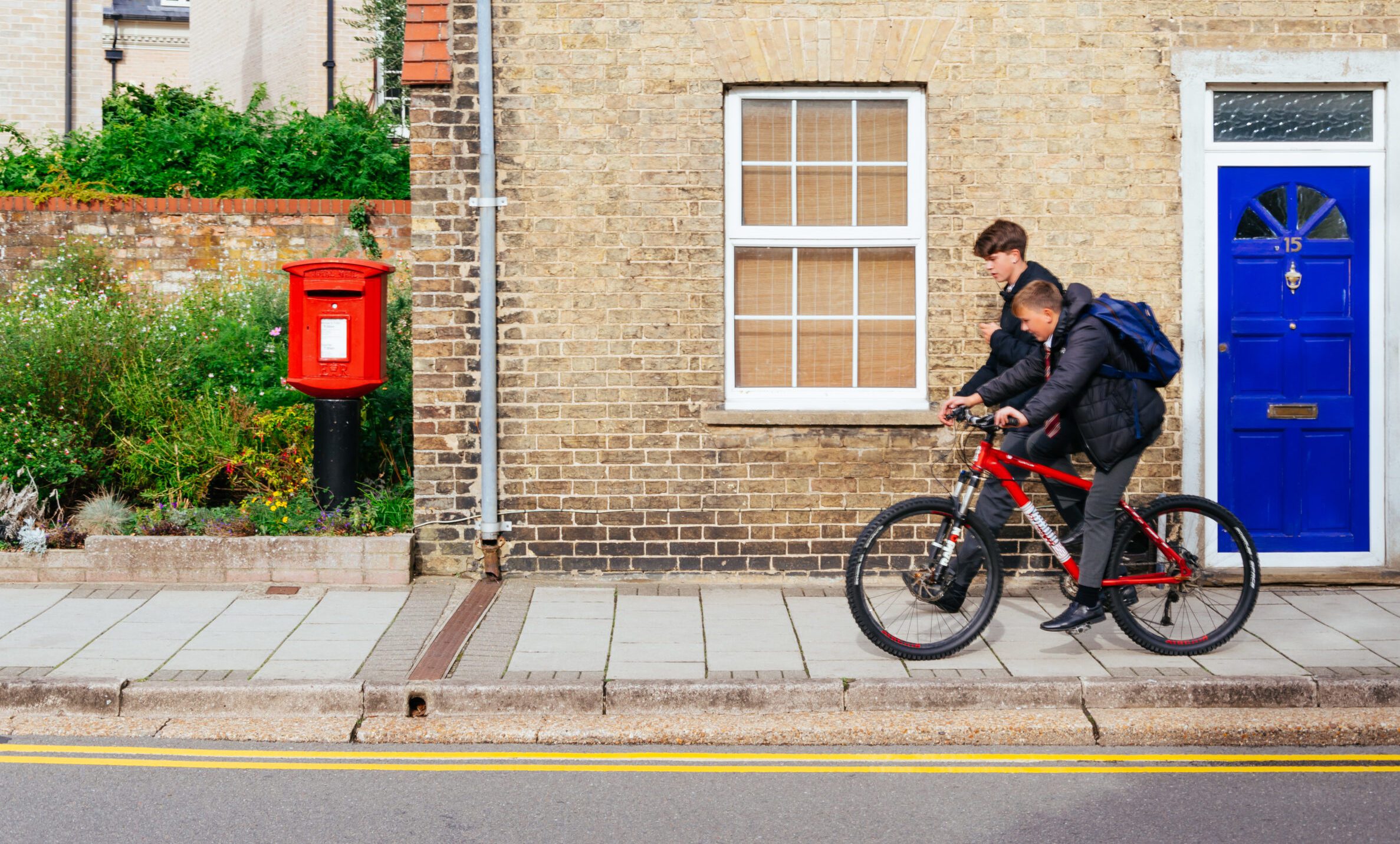 Two teenage boys in school uniform on bikes