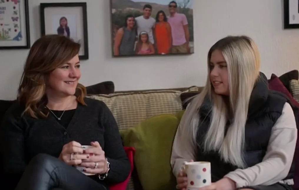 Two adults talking holding coffee cups